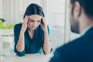 Image of two workers at a meeting in a restaurant. Young pretty exhausted businesswoman having headache because of problems at work