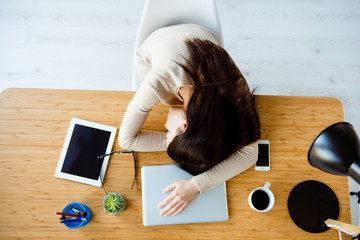 Top view portrait of young overworked businesswoman sleeping at the table