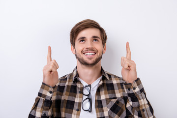 Handsome young smiling man in checkered shirt showing up on copyspace.