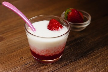 Strawberry flavored tapioca pudding served in glass cup on darkwood table