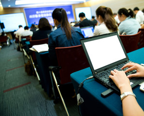 Business people typing on laptop keyboard at conference.