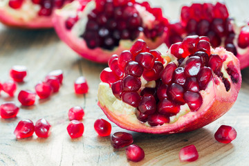 pieces of red pomegranate on the wooden background 