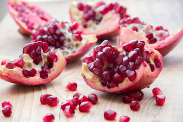 pieces of red pomegranate on the wooden background 