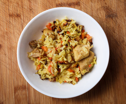 Pilaf - rice with meat and vegetables on a wooden table
