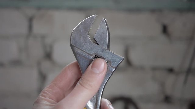 Brilliant adjustable spanner  and male hands in work.  
