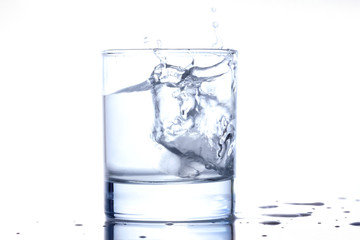 blue water splashing out of a glass with drops