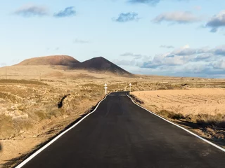 Zelfklevend Fotobehang Lonely, remote road at sunset running trough a deserted landscape with volcano mountains on the Canary Islands. © sotavento1000