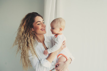 happy family at home. Mother holding baby son in bedroom in cozy weekend morning