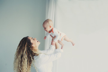 happy family at home. Mother holding baby son in bedroom in cozy weekend morning