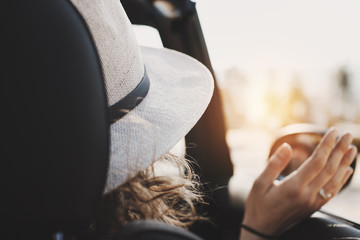 Girl with curly hair in a hipster hat sits in a cabriolet on the passenger seat. Sunlight  and flare effect