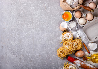 Fototapeta na wymiar Fresh Ingredients for Cooking Traditional Italian Pasta Tagliatelle.Flour,Eggs,olive oil on a grey stone Background.Copy space for Text. selective focus.