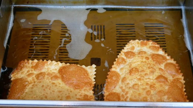 4K footage of Tatar, Turkish, Ukrainian, Russian and Asian Cig Borek or Chebureki street food or snack frying in hot oil by professional cook