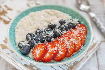 healthy oatmeal with shredded coconut, blueberries and strawberries