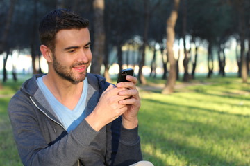 Joyful male texting in the park