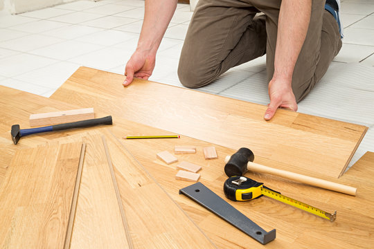 young man at parquet flooring work / junger mann beim verlegen von Parkett