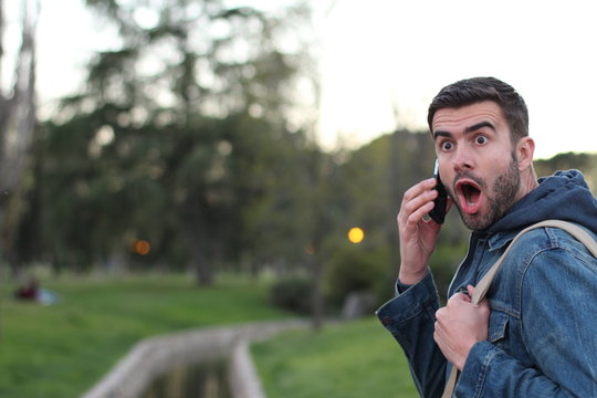 Male getting shocking new on the phone outdoors
