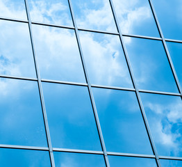 Sky and clouds reflected in windows of modern office building.