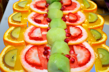 Sweet wedding table decorated with thin cutouts of strawberries, bananas, pineapple, kiwi, of grapefruit, oranges and raspberry