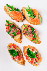 Six bruschettes with greens, cheese, meat and fish