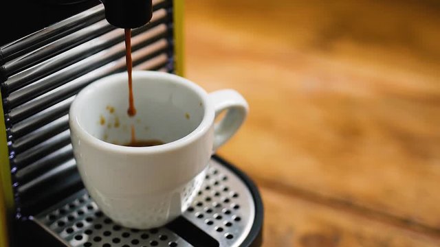 pour coffee with coffee maker in a white cup on a wooden floor in the kitchen at the breakfast