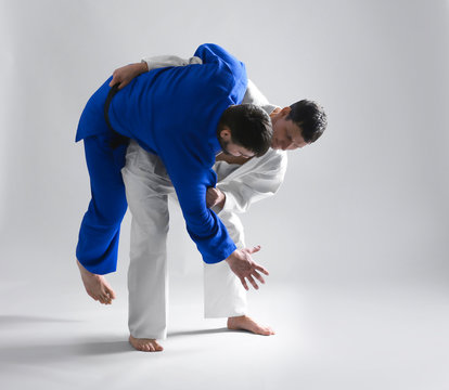 Young sporty men practicing martial arts on light background