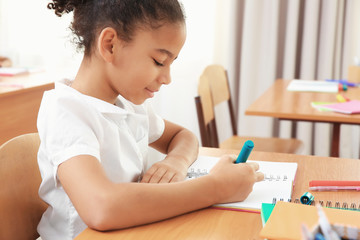 Beautiful elementary schoolgirl studying in classroom