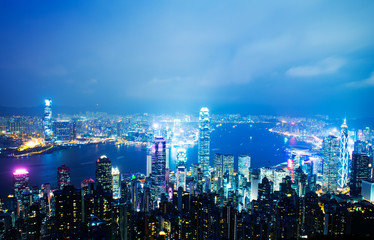 Hong Kong cityscape at night with victoria harbour and large group of tall buildings.