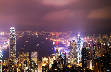 Hong Kong cityscape at night with victoria harbour and large group of tall buildings.