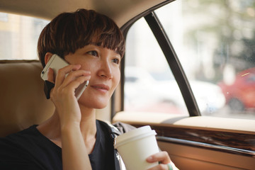 Asian woman making a phone call in cab