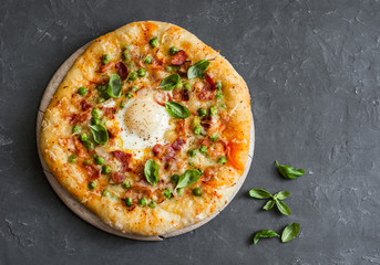 Pizza with bacon, egg and green peas. Breakfast pizza on a gray background, top view. Free space