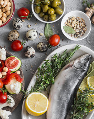 Mediterranean style food. Fish, vegetables, herbs, chickpeas, olives, cheese on grey background, top view. Healthy food concept. Flat lay