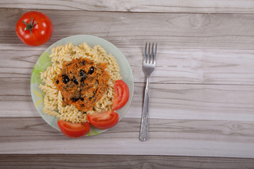 Boiled spaghetti with vegetables and tomatoes on a wooden table