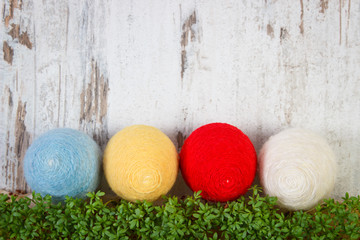 Easter eggs wrapped woolen string and green cress on wooden background, copy space for text, decoration for Easter
