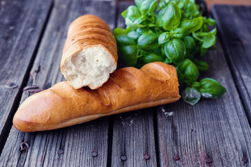 French baguette and green basil on a grey wooden table.
