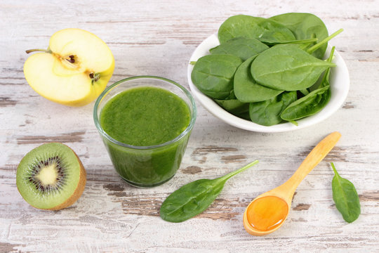 Ingredients and fresh cocktail from spinach, apple and kiwi on wooden background, healthy nutrition