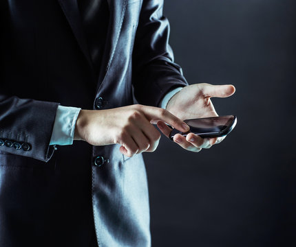 closeup of a businessman presses a finger on the smartphone screen.
