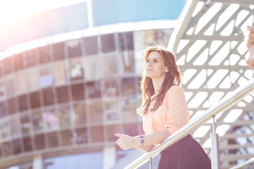 successful business woman standing on the balcony of the modern office and looks into the distance.