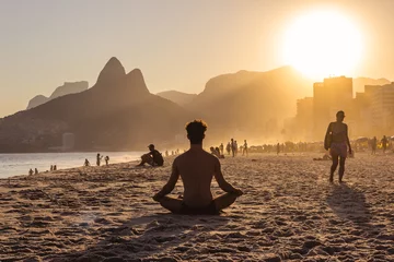 Foto op Plexiglas Man op yoga pose tijdens een zonsondergang op het strand van Ipanema met Morro Dois Irmãos op de achtergrond, Rio de Janeiro, Brazilië © AnaClaraTito