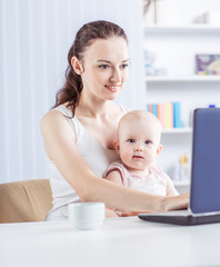 young mother and baby using laptop to communicate with grandma via skype