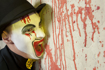 Evil clown wearing a bowler hat on wall