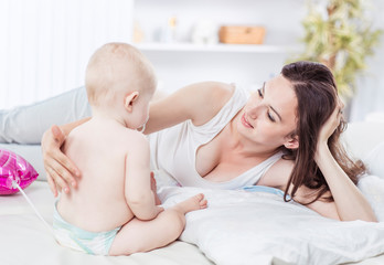 portrait of happy mother and year-old baby on the bed in the bedroom