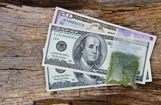 Dollars and marijuana in packet on wooden background