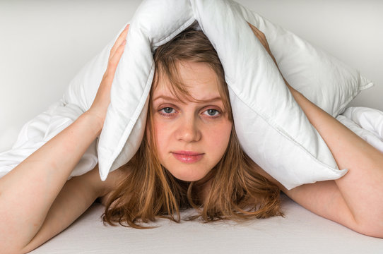 Woman trying to sleep, she covering ears with pillow