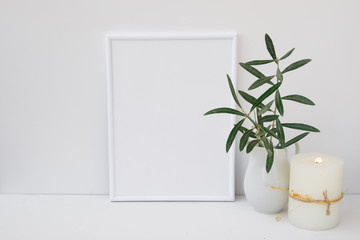 Frame mockup on white background, olive tree branches in ceramic pitcher, candle, styled image for social media, marketing