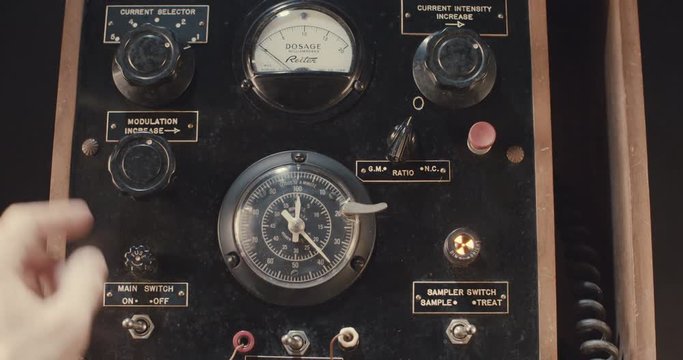 Hand operating old electrical equipment with dials and switches