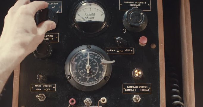 Hand operating old electrical equipment with dials and switches