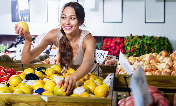 Positive young woman buying fresh lemons