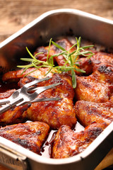 Chicken wings baked in a pan on wooden background