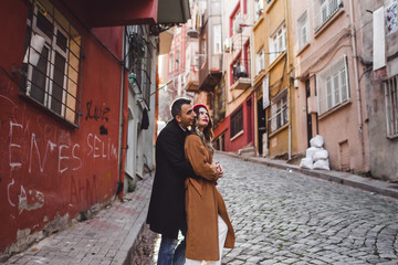 Fototapeta na wymiar European couple walking at old Istanbul streets. Casual style, red beret and beige coat