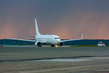 Fototapeta na wymiar Airplane heading to follow me car on the main taxiway to the background of the morning rain